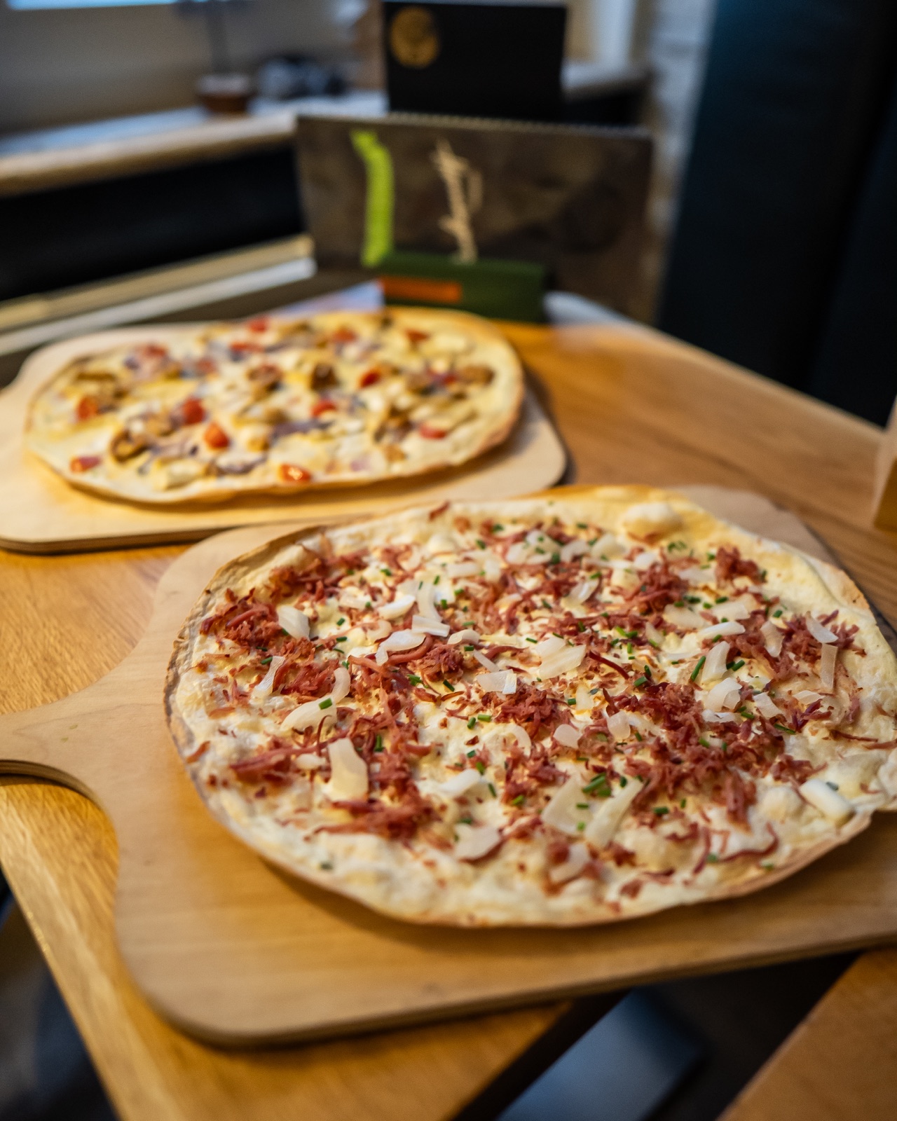 Frisch zubereitete Flammkuchen auf Holzbrettern